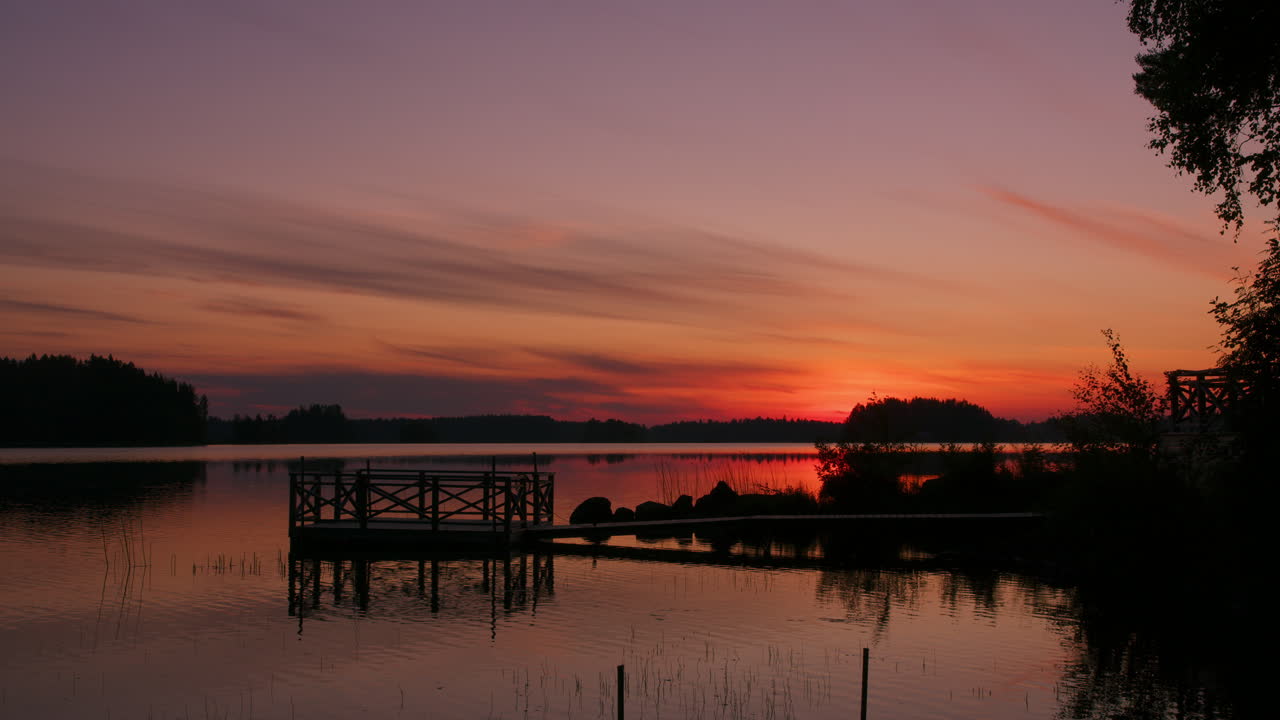 Zeitrafferaufnahme eines wunderschönen Sommer-Sonnenaufgangs in Nordschweden, warmer, hoffnungsvoller Morgen, farbenfroher Sonnenschein, Wasser und Himmel, See in der Natur, statische 4K-Zeitrafferaufnahme in der Morgendämmerung
