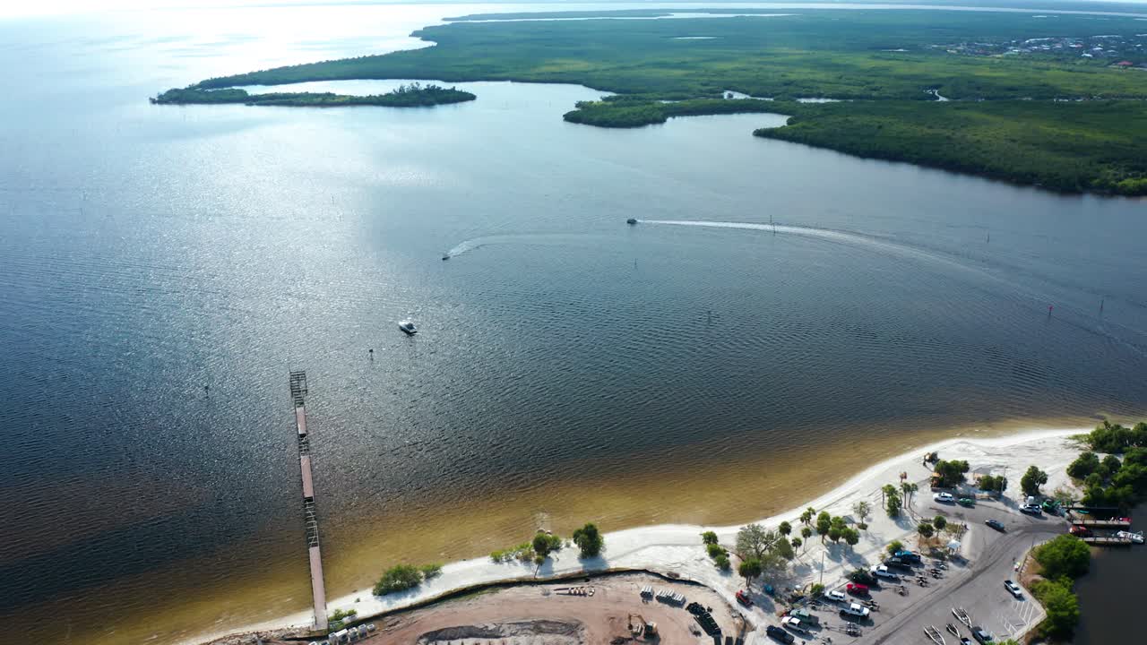 Kystnær byggeplads ved siden af en bugt med parkeringsområder, både og dokker, omgivet af grøn vegetation og roligt vand i et naturligt miljø