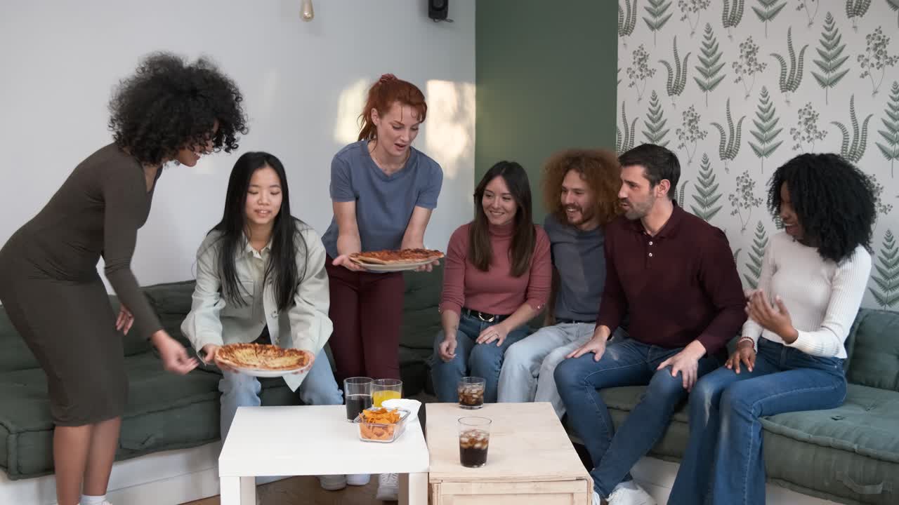Black woman bringing pizza to friends in living room