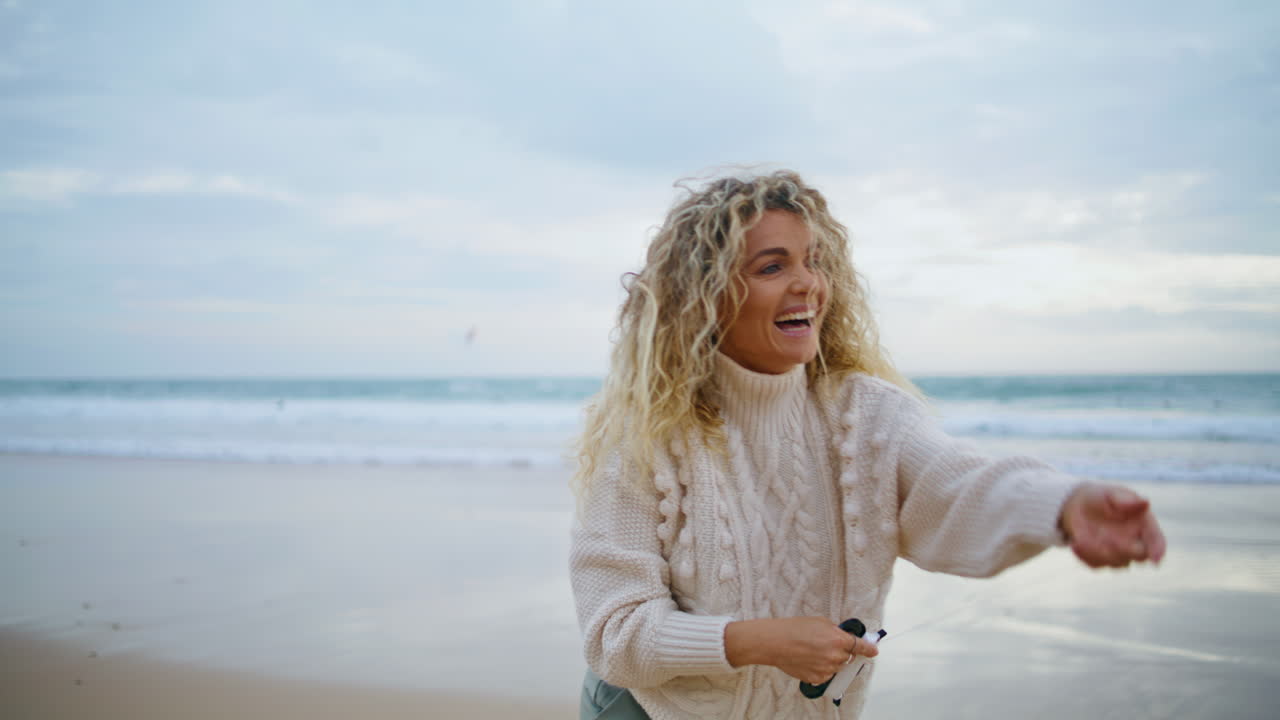 Romantic girl holding kite string at beautiful ocean view. Cheerful mother play