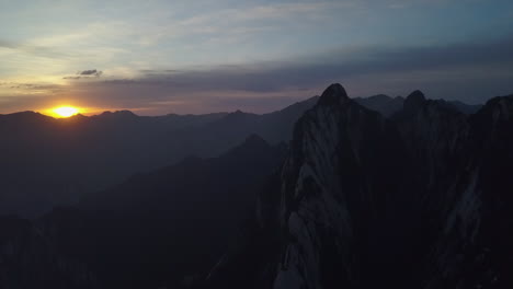 rugged granite mountain range with golden sunset behind distant peak