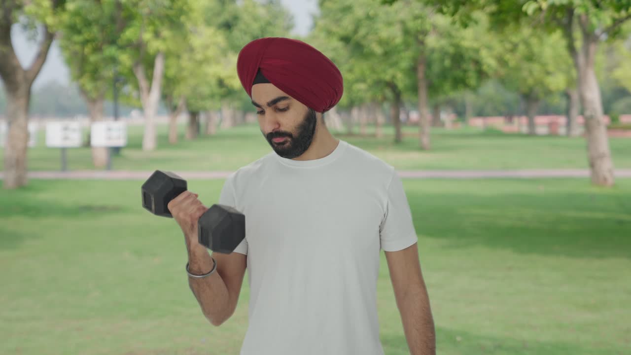 hombre indio sikh levantando pesadas pesas en el parque