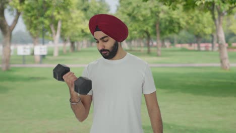 sikh indian man lifting heavy dumbbells in park