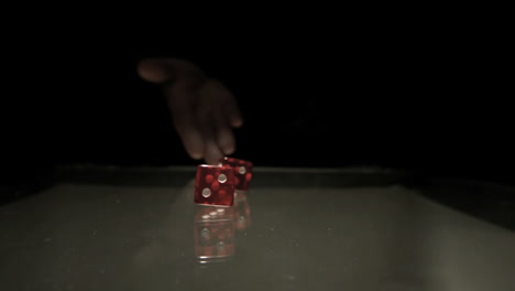 mano lanzando dos dados rojos sobre la mesa