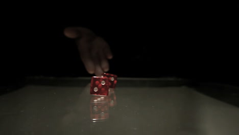 hand throwing two red dice onto table