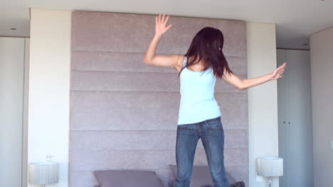 gorgeous brunette jumping on her bed