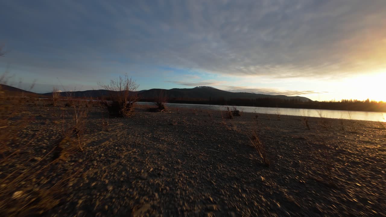 Witness the breathtaking beauty of Yakutia as the warm light of dawn illuminates tranquil waters and rugged terrain. Experience nature’s calm and untouched splendor from above.