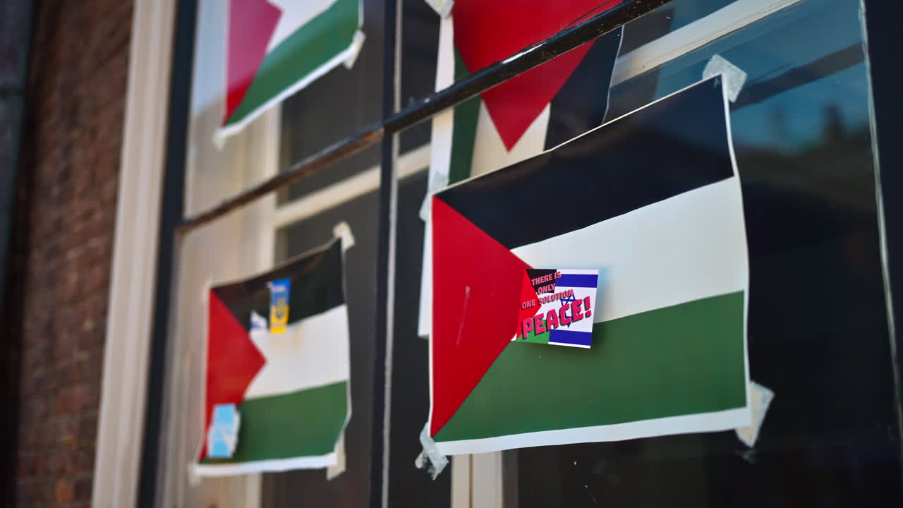 Multiple small flags of Palestine proclaiming peace, taped on a window in Copenhagen, Denmark