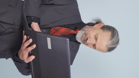 vídeo vertical del viejo hombre de negocios se relaja después de terminar su trabajo en la computadora portátil.