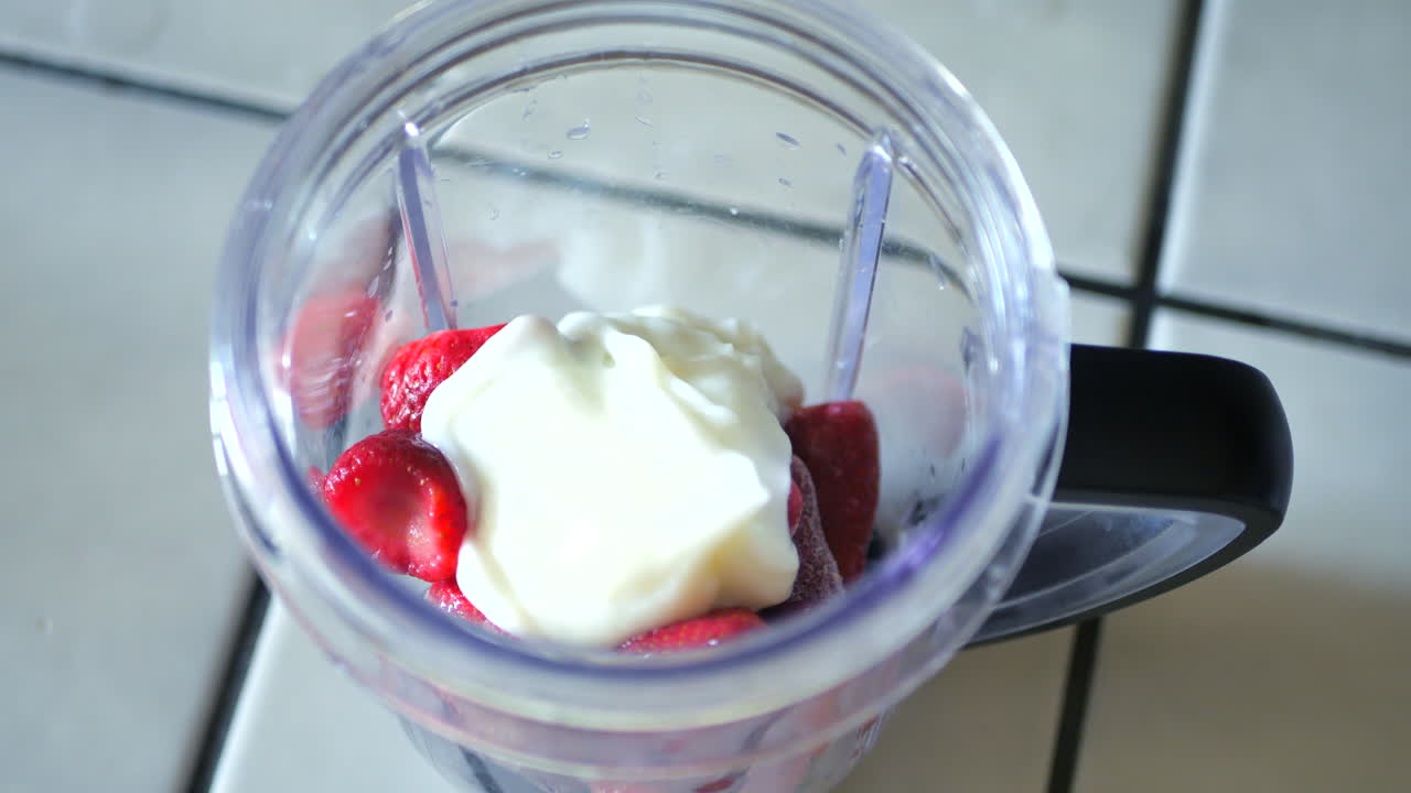 verter yogur, arándanos y fresas congelados en la licuadora para hacer batidos o batidos de fitness