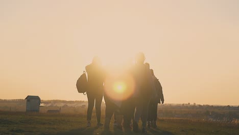 people silhouettes walk along meadow in early morning