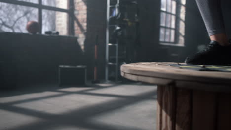 muscular woman doing jumps on wooden box. athlete practicing physical exercises