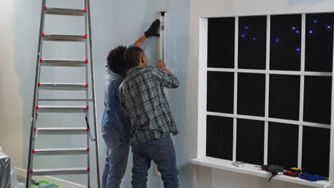 black constructors check wall with level working in studio