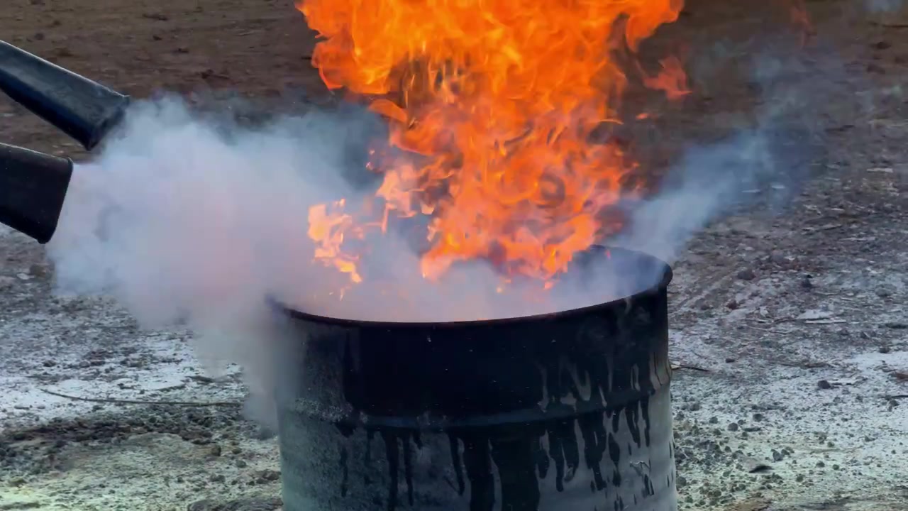 Brandslukker sprøjter hvid røg for at slukke flammer i en metalbeholder. Optagelser af brandsikkerhed, beredskab og brandslukningskoncept