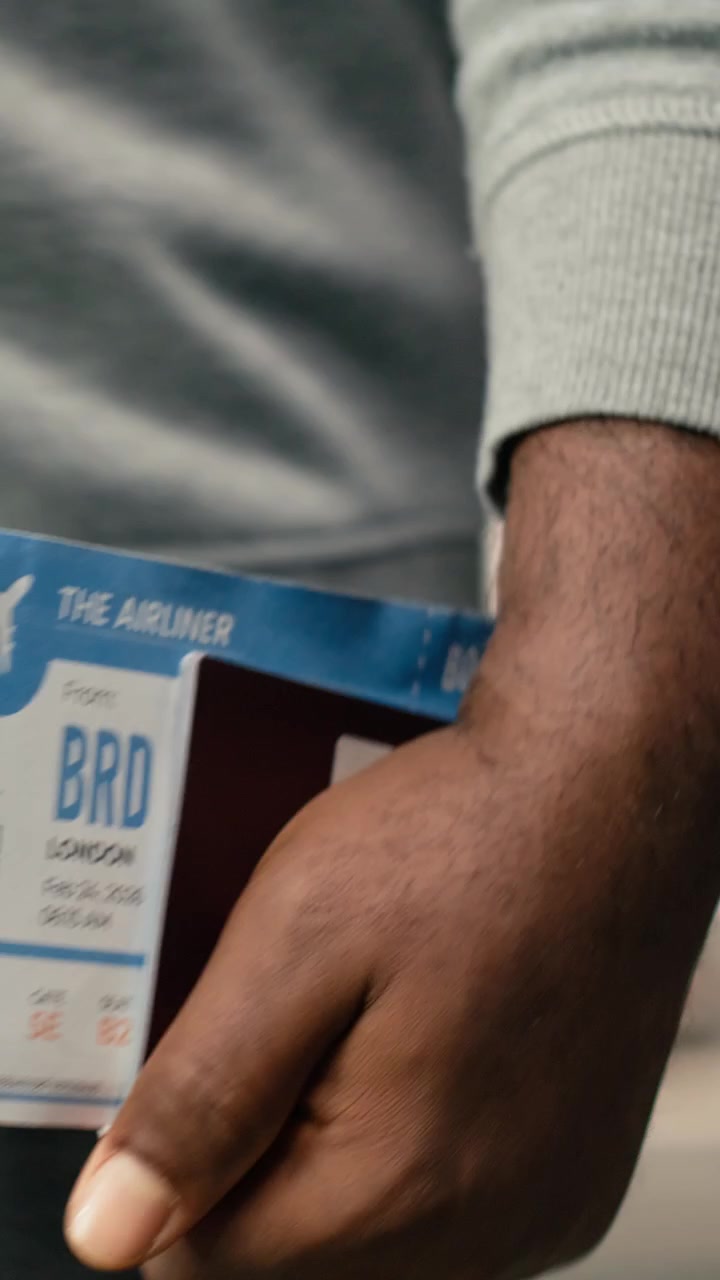Vertical video Close up of plane ticket and passport held by man walking in airport terminal
