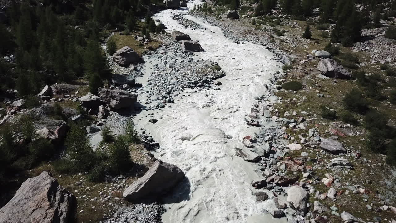 vista aérea de drones de un río fangoso en los alpes suizos, valle de montaña rocosa, fuerte corriente y olas