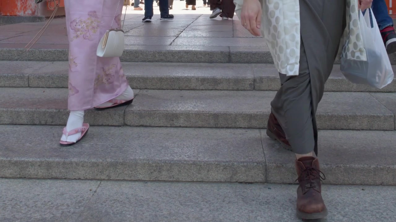 Low angle shot of people in traditional dress and casual wear descending stone shrine steps.