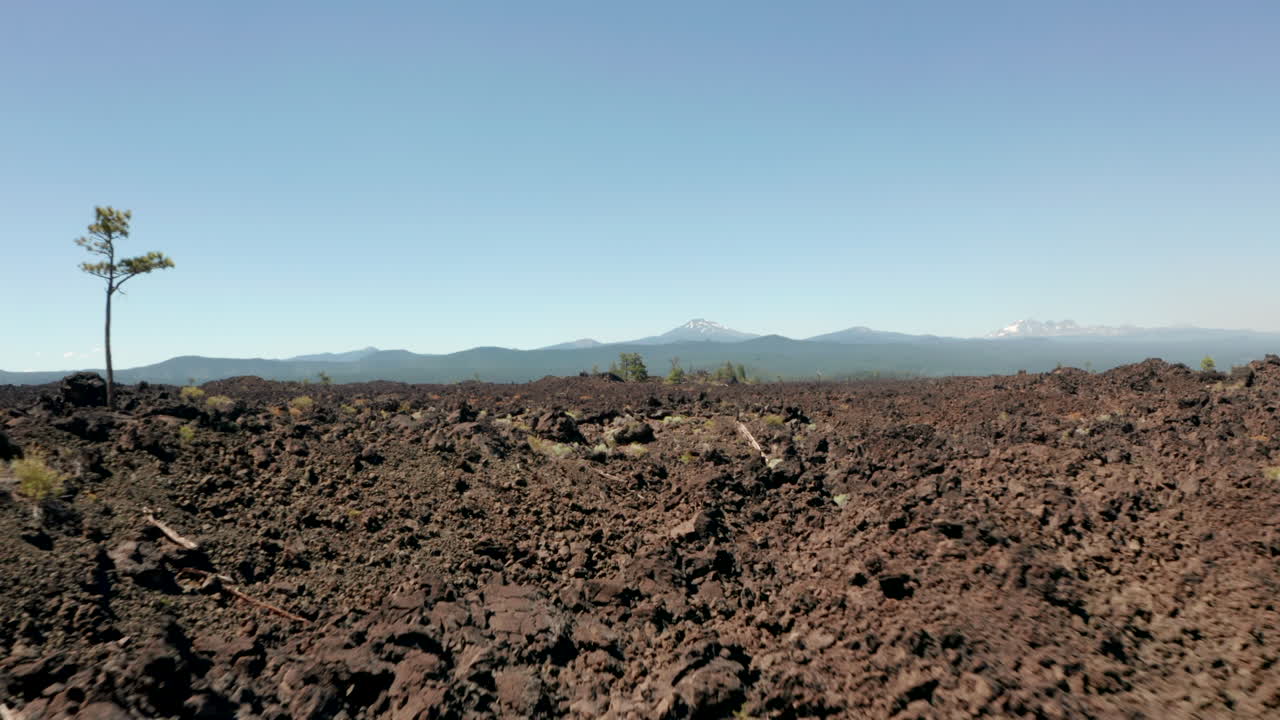 tiro aéreo bajo sobre campos de lava rocosa hacia un volcán de estrato extinto