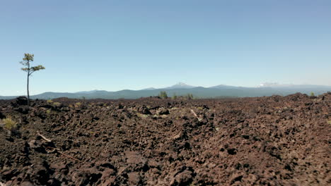 Low-aerial-shot-over-rocky-lava-fields-towards-an-extinct-strato-volcano