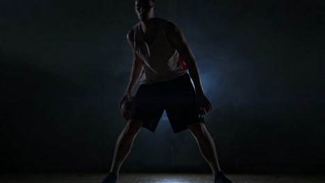Dribbelnder-Basketballspieler-Auf-Dem-Spielfeld-Mit-Dem-Ball-In-Einem-Dunklen-Raum-Mit-Hintergrundbeleuchtung-In-Zeitlupe-Im-Rauch