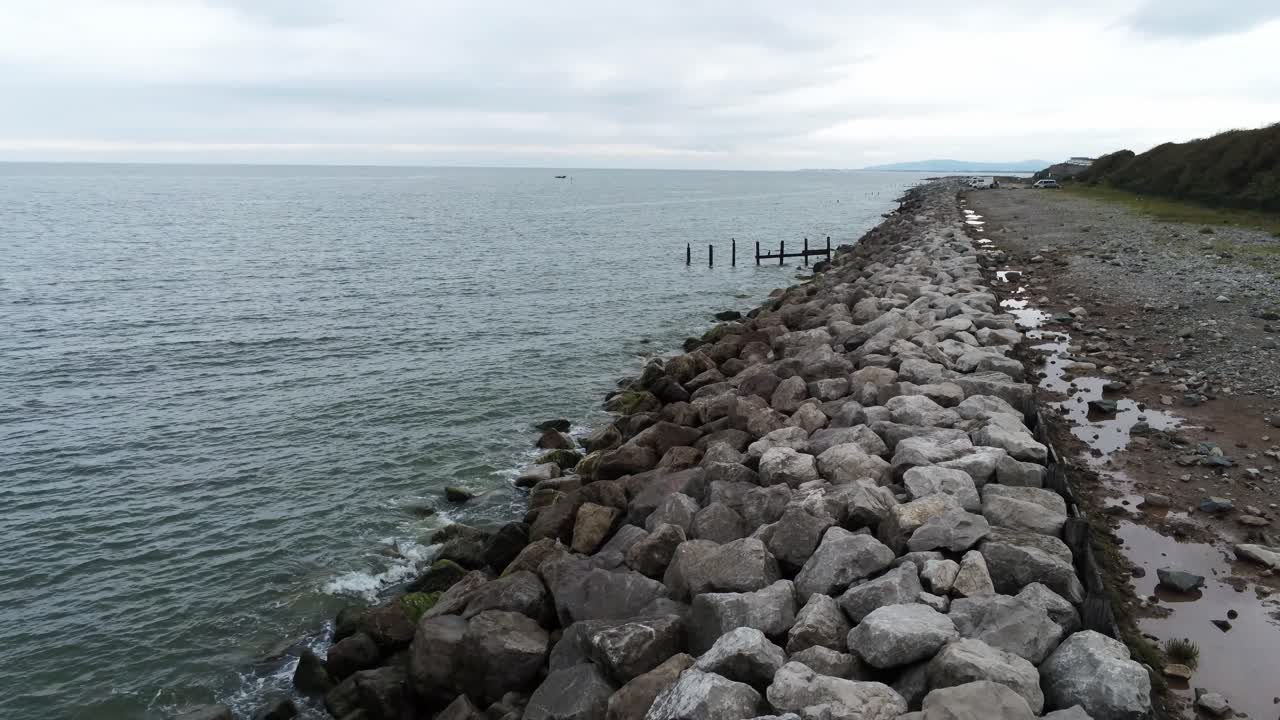 vista aérea baja hacia atrás por encima de las salpicaduras de la marea del océano rompiendo en la costa rocosa rápidamente