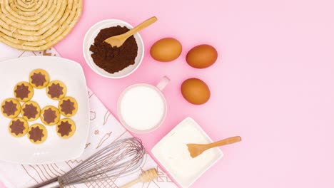 ingredients for baking and cookies in plate appear on left side of pink theme. stop motion