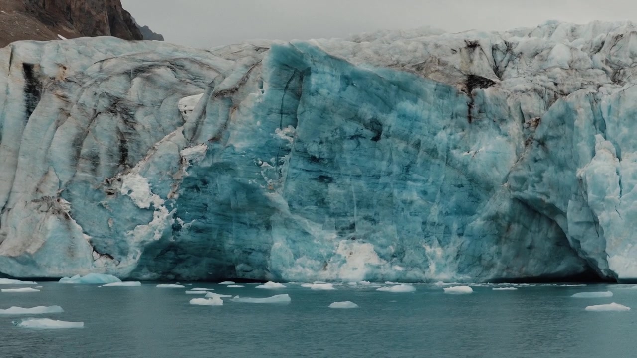 Parete di ghiacciaio blu che si erge sopra acque polari ghiacciate con blocchi di ghiaccio marino galleggianti