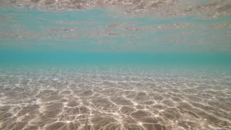 blue sea water sunny refractions on sandy bottom, underwater loop-ready background