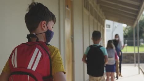 Gruppe-Von-Kindern-Mit-Gesichtsmaske,-Die-In-Einer-Warteschlange-In-Der-Schule-Stehen