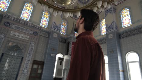 A young bearded man standing watching the ceiling of the mosque, Muslims who go to historical and holy places pray