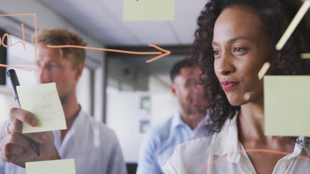 Professional businesswoman sticking memo notes on glass-board in modern office in slow motion