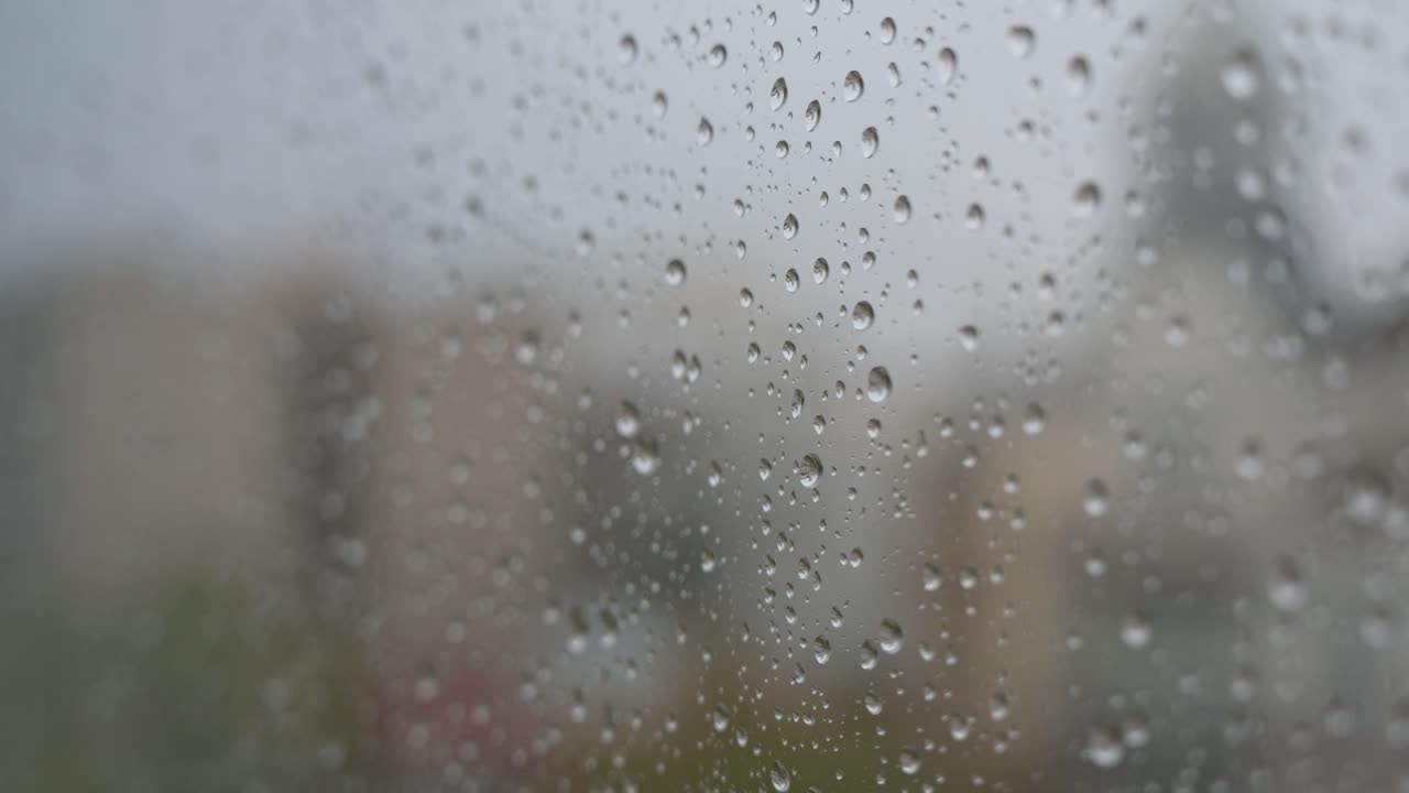 Raindrops on a window looking out to gloomy, overcast weather