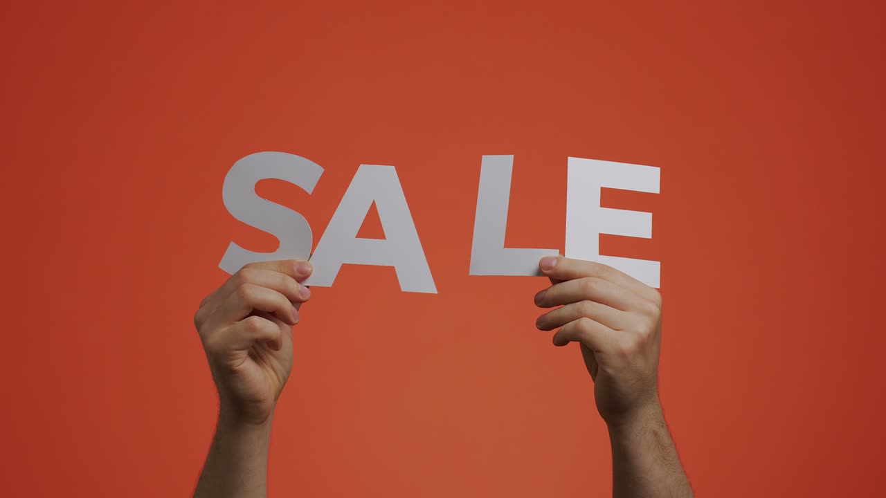 anuncio de venta. hombre mostrando el letrero de venta en chromakey naranja. oferta de descuentos en la tienda. concepto de compras baratas