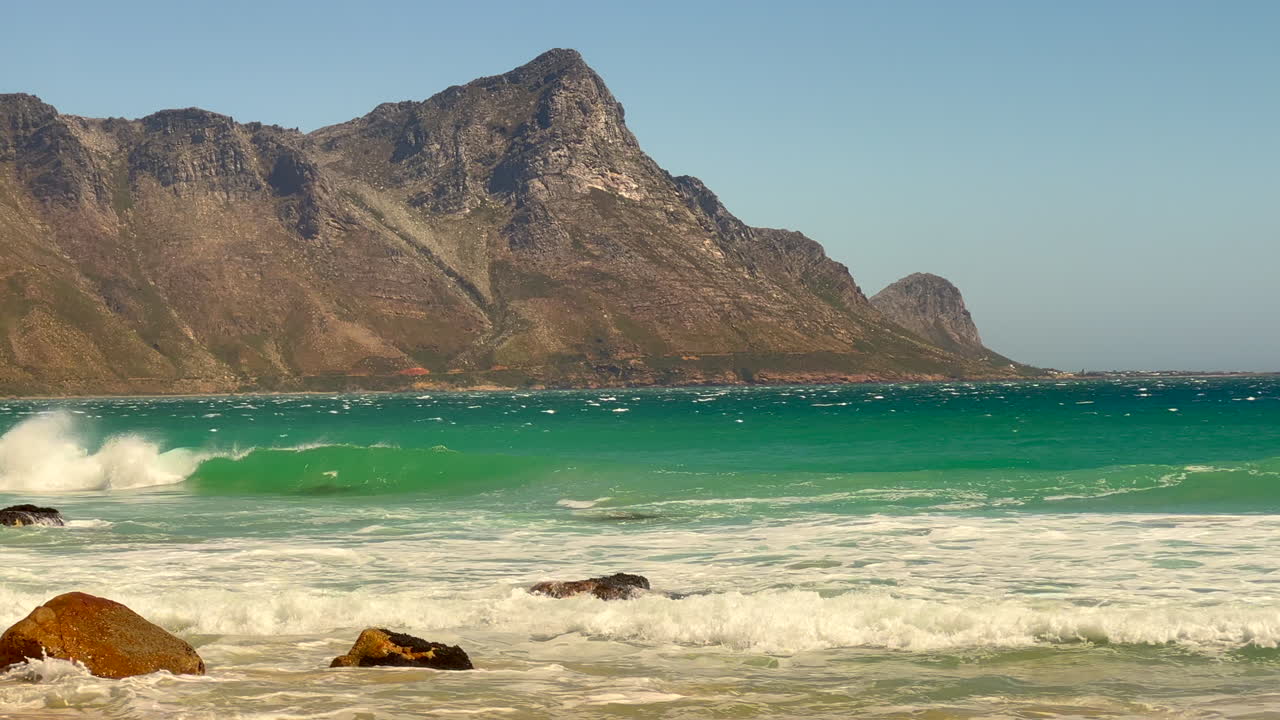 Koeel Bay Dappat Se Gat cinematic windy polarized surf waves crashing stunning Kogel Bay Beach Cape Town South Africa coastline aqua deep blue water Gordon's Bay Garden Route forward pan left