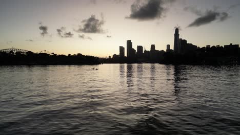 Sydney-CBD-Während-Des-Sonnenuntergangs-Mit-Zwei-Paddelnden-Kajaks