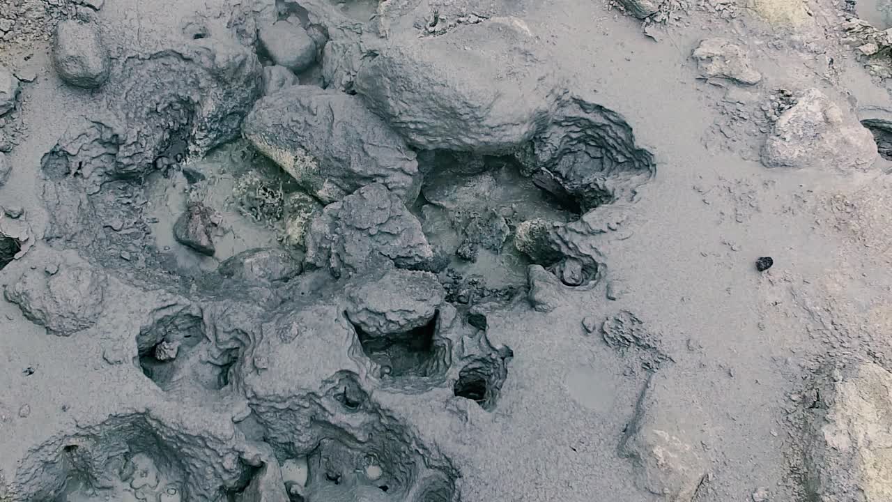 Muddy active bubbling geothermal formation and grey hot springs, close up pan