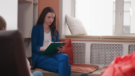 la psiquiatra hace notas sentada en la sesión con el cliente. la mujer enfocada escucha al paciente escribiendo atentamente observaciones en el cuaderno. problemas familiares
