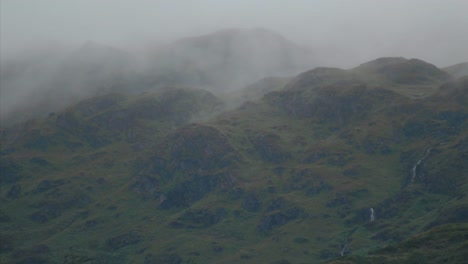 timelapse of low hanging clouds passing through moody highland mountains