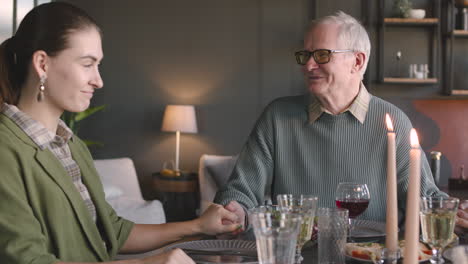 old man and his two adult daughters sitting at dinner table and being ready to eat after thanksgiving prayer