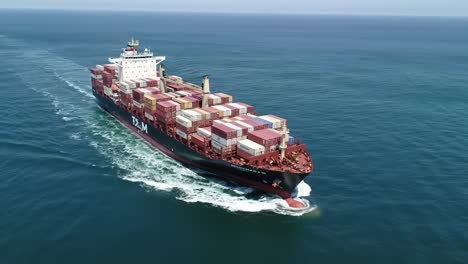 container ship navigating open waters, stacks of cargo containers on deck, and clear blue skies displaying maritime transportation at sea