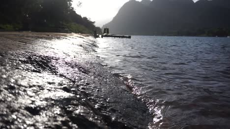 primer plano disparó agua golpeando la orilla contra la puesta de sol