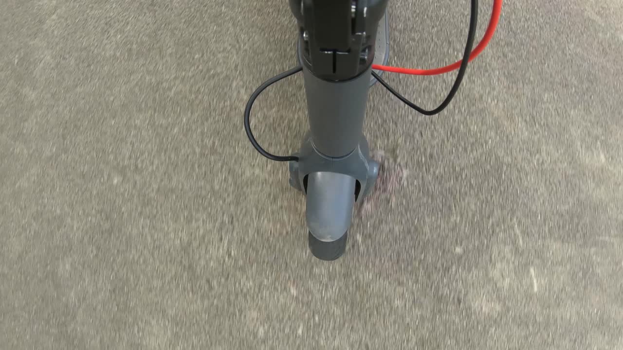 Point Of View On The Front Wheel Of An Electric Scooter Driving On Concrete Path