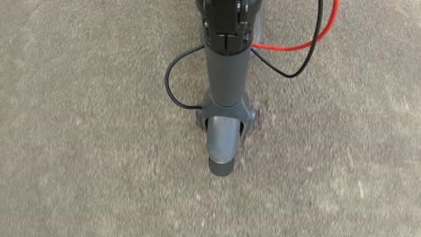 punto de vista sobre la rueda delantera de un scooter eléctrico conduciendo por un camino de hormigón