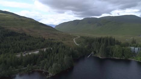 aerial pullback shot over loch ossian looking north towards the hills on a cloudy and moody day