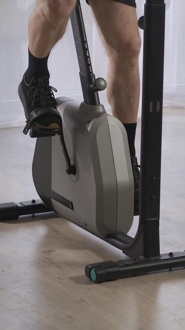 Piernas de hombre pedaleando en una bicicleta estática durante un entrenamiento en casa