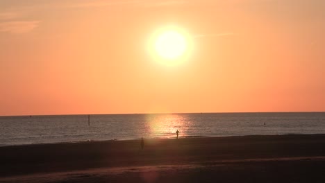 Spectacular-orange-sunet-over-ocean-with-waves-breaking-on-beach-aerial-view