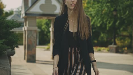 beautiful young female model in casual black outfit turning back walking towards the camera - slow motion