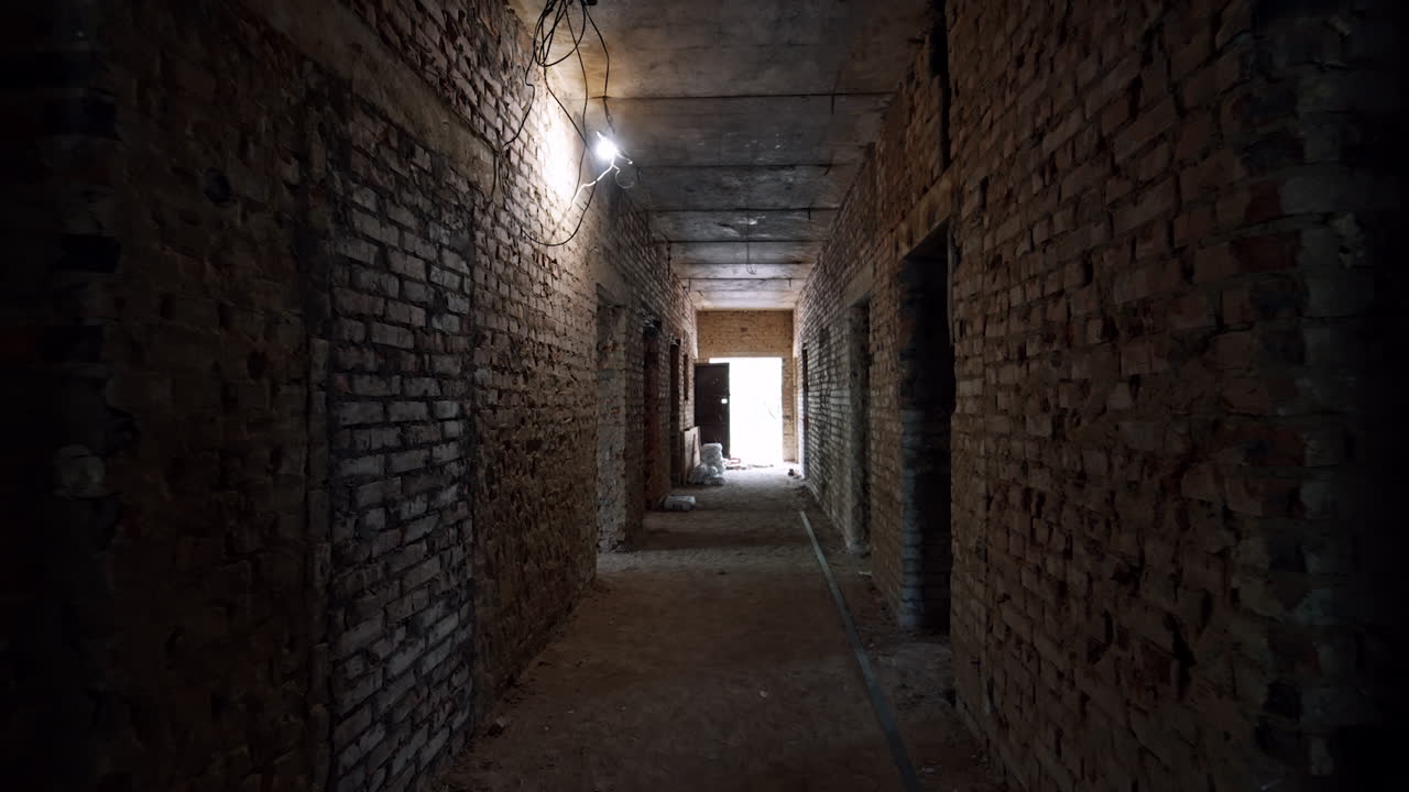 Moving by the long corridor in the old building with brick walls. Materials for interior works are in the hall.