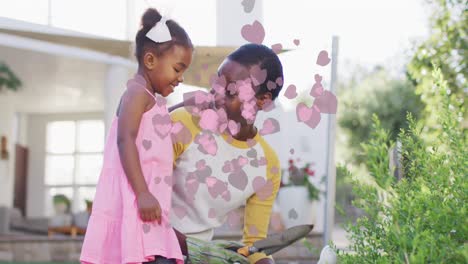 animación de iconos de corazón sobre feliz madre y hija afroamericana jardinería