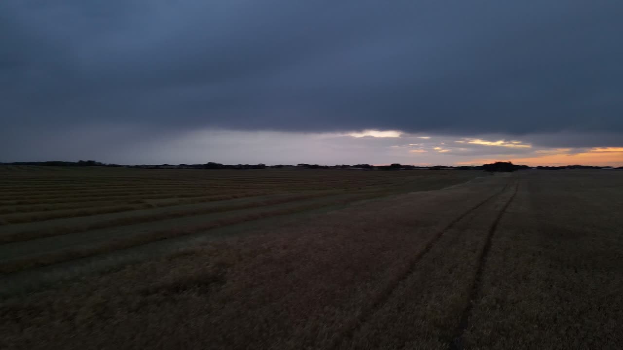 Panorerande drönarflygning över platt, vidsträckt jordbruksmark på den nordamerikanska landsbygden vid skymningen